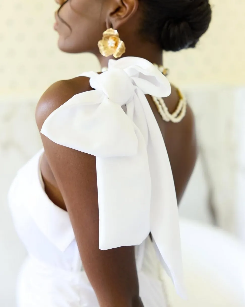 Mariée de dos, grand nœud blanc sur l'épaule et boucle d'oreille dorée
