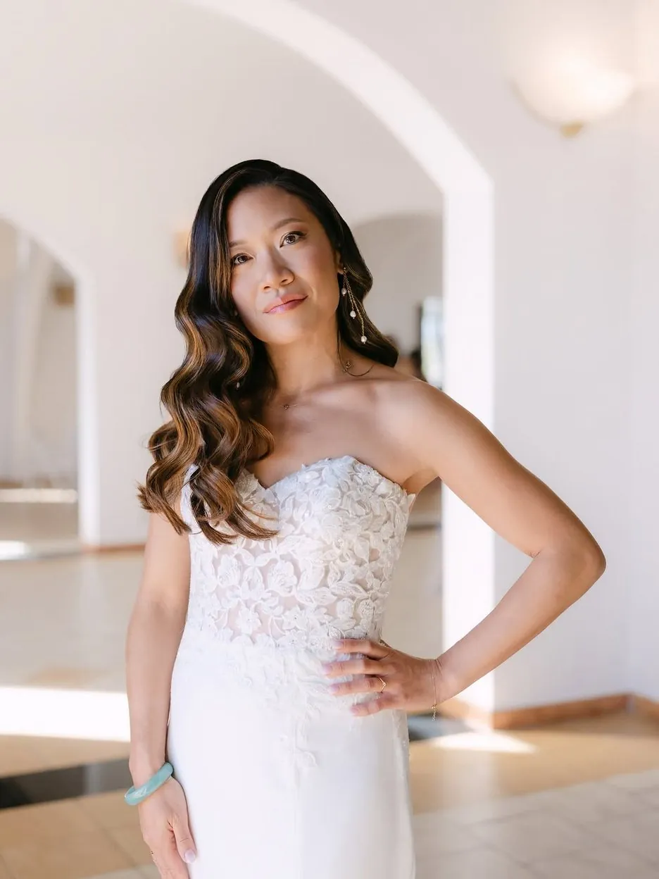 Portrait de la mariée, la main sur la hanche, dans une galerie voûtée