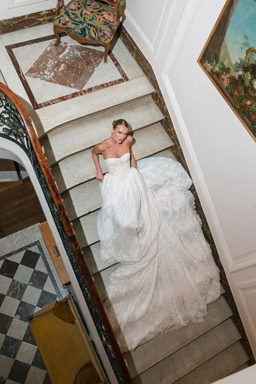 Mariée vue d'en haut, assise dans un escalier, sa robe étalée sur les marches