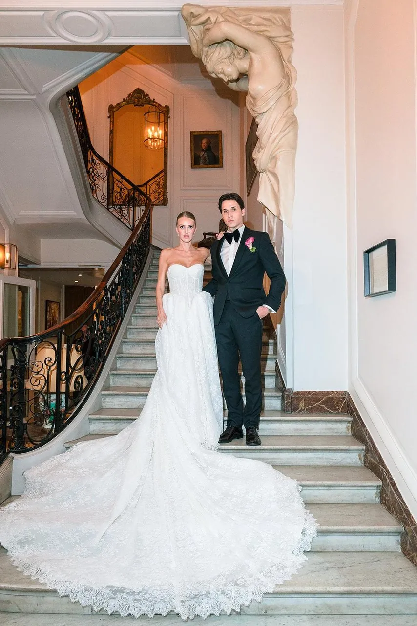 Couple posant dans un grand escalier de marbre, la traîne de la robe déployée